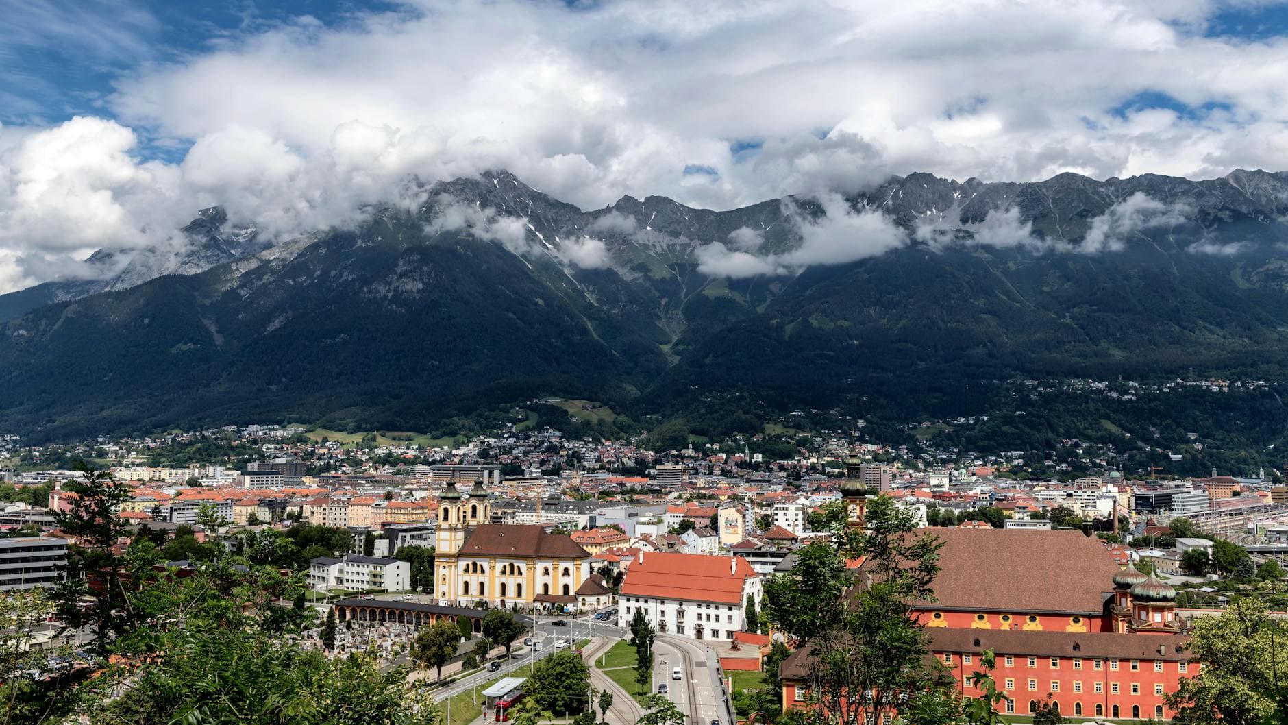 Innsbruck gezien vanuit de Nordkette — barokke stadskern met de Inn en de omringende Tiroolse Alpen in blauw en groen.
