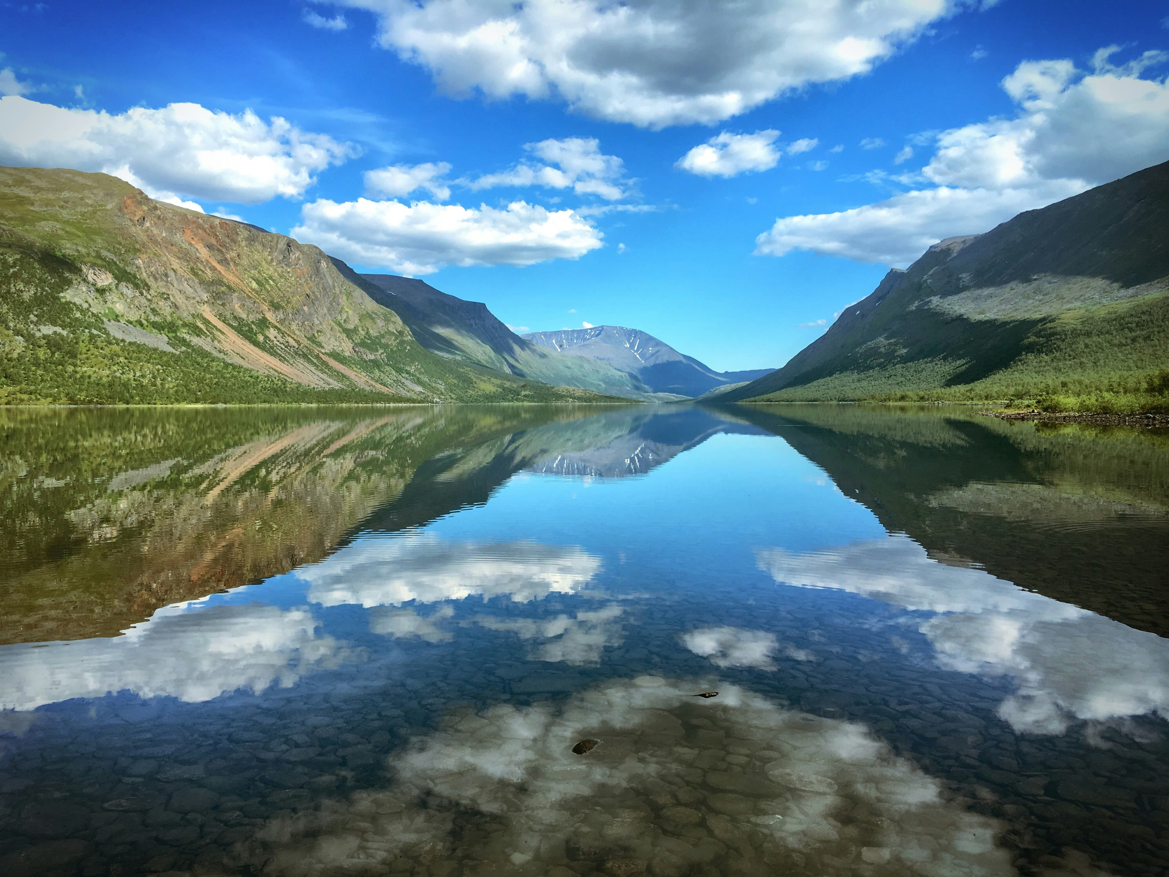 Noors fjordlandschap met spiegelstil water en bergwanden — wolkenreflectie in het kristalheldere fjordwater, zomerlicht.